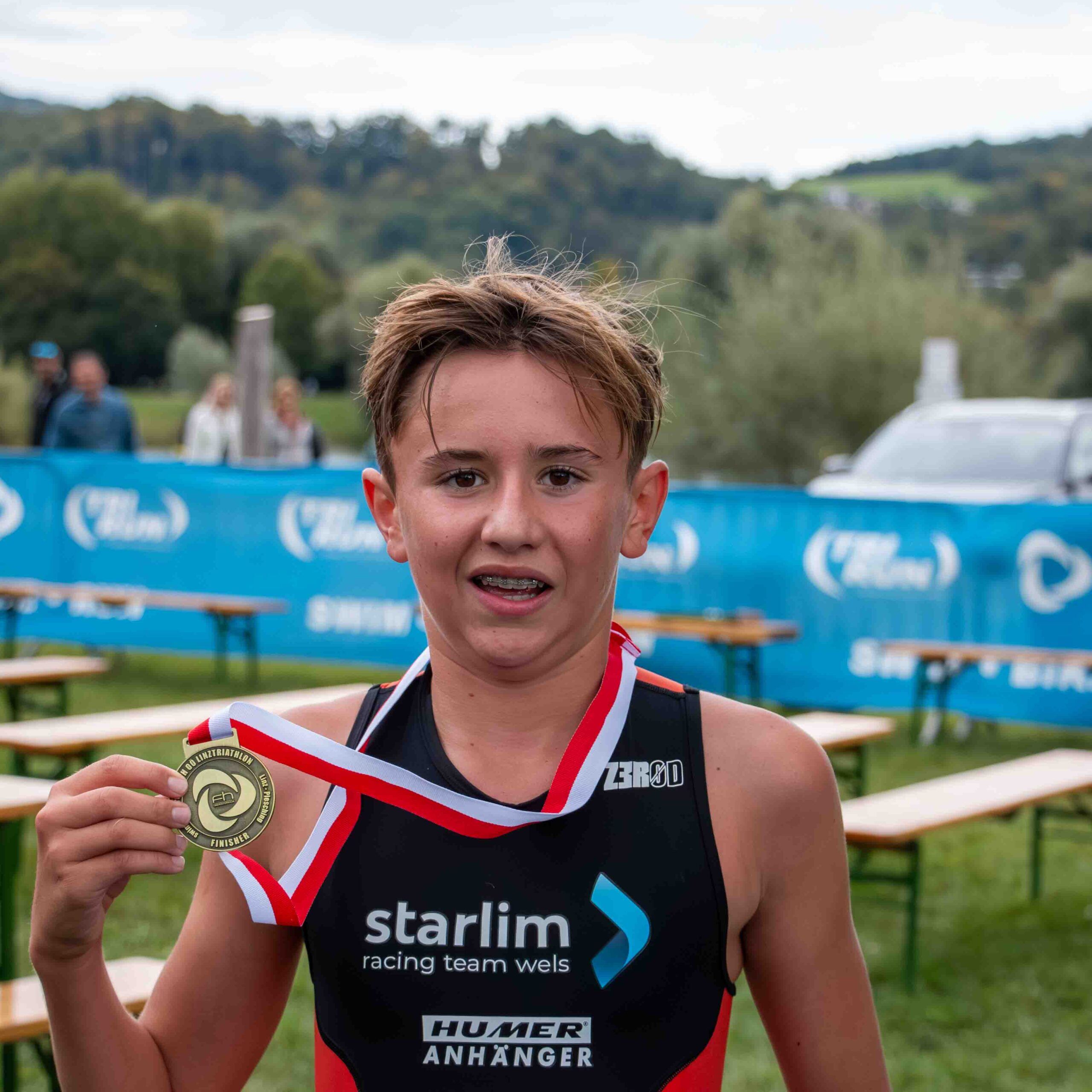 Triathlet zeigt stolz seine Medaille vom Aquathlon Linz