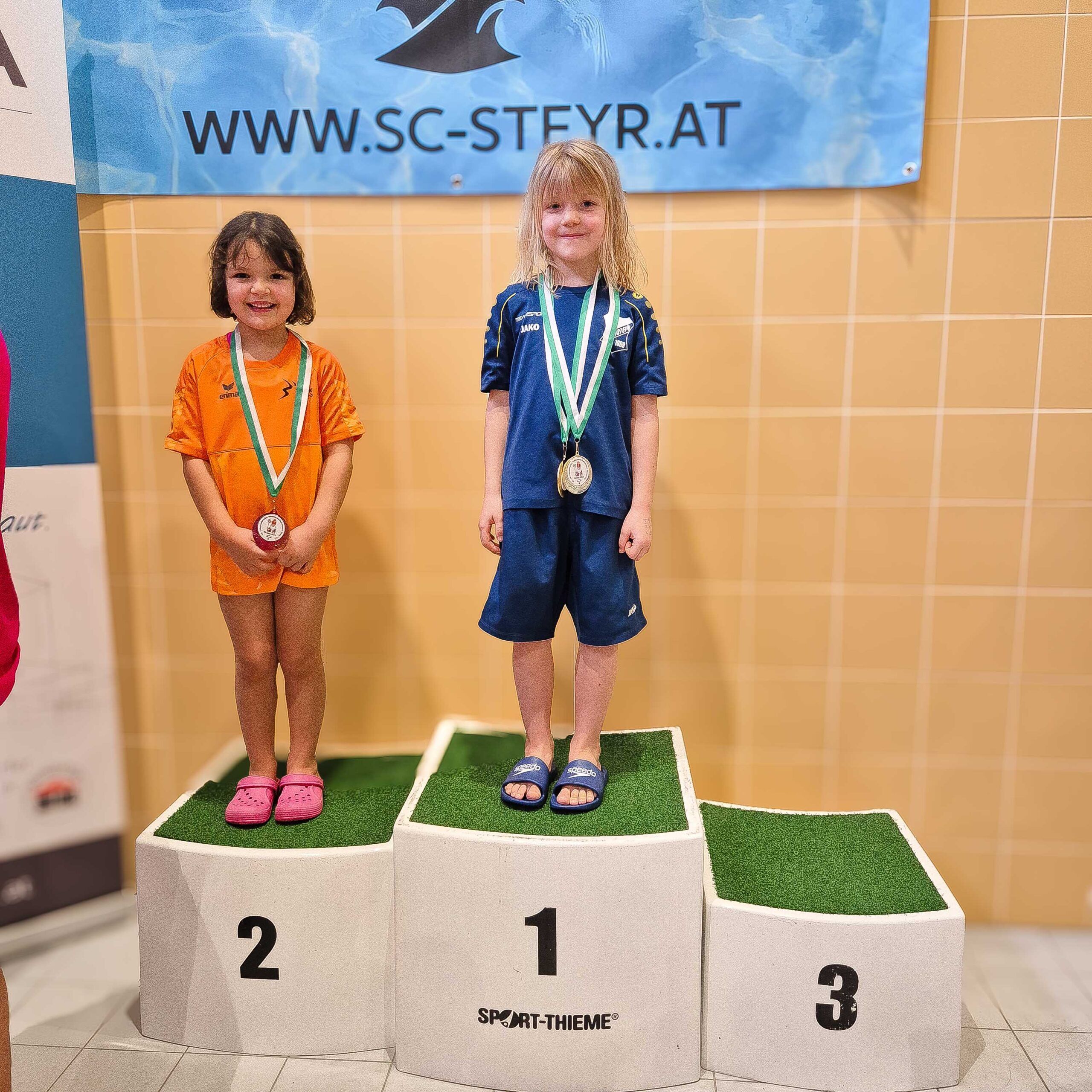 Zwei Kinder stehen am Siegerpodest